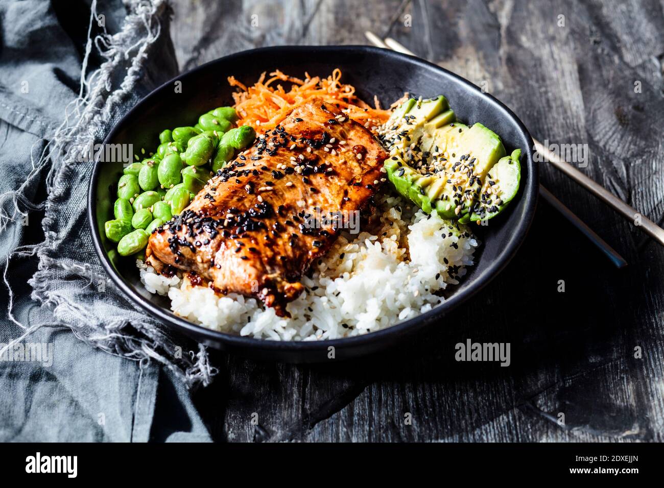 Schüssel Teriyaki Lachs mit Reis, Karottensalat, Edamame-Bohnen, Avocado und Sesam Stockfoto