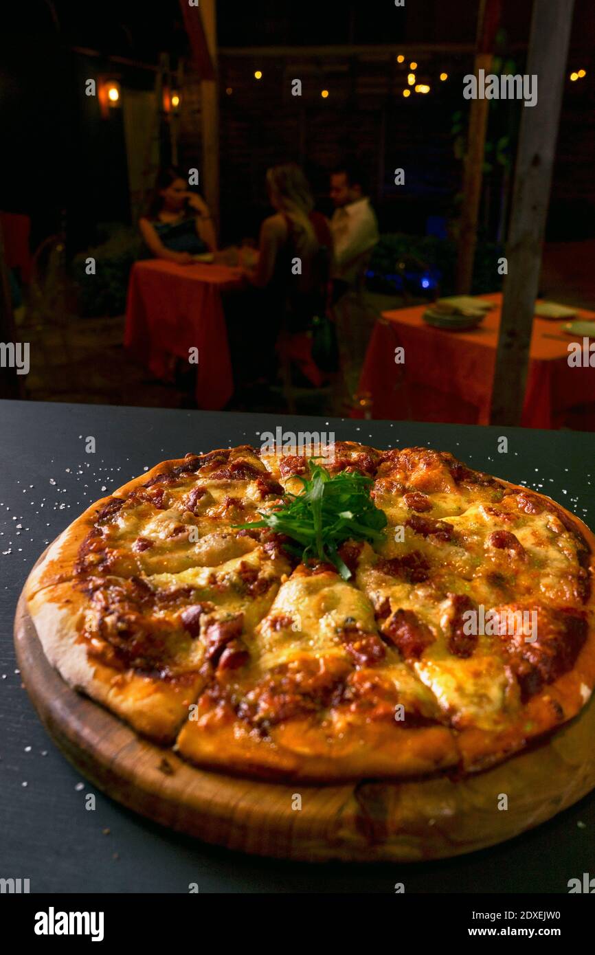 Draufsicht traditionelle knusprige italienische Pizza mit Käse und Chistorras schwarz rustikalen Holzhintergrund. Blick von oben auf heiße Pizza. Restaurant verwischen Hintergrund Stockfoto
