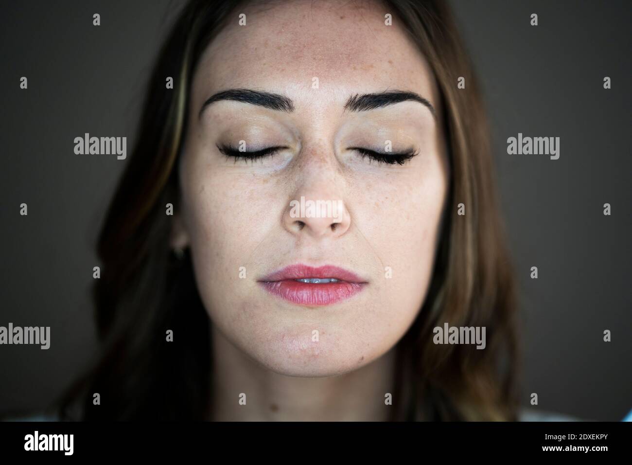 Junge Frau mit geschlossenen Augen im Studio Stockfoto