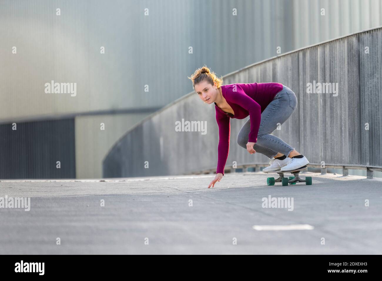 Junge Frau Skateboarding auf Fußgängerbrücke Stockfoto