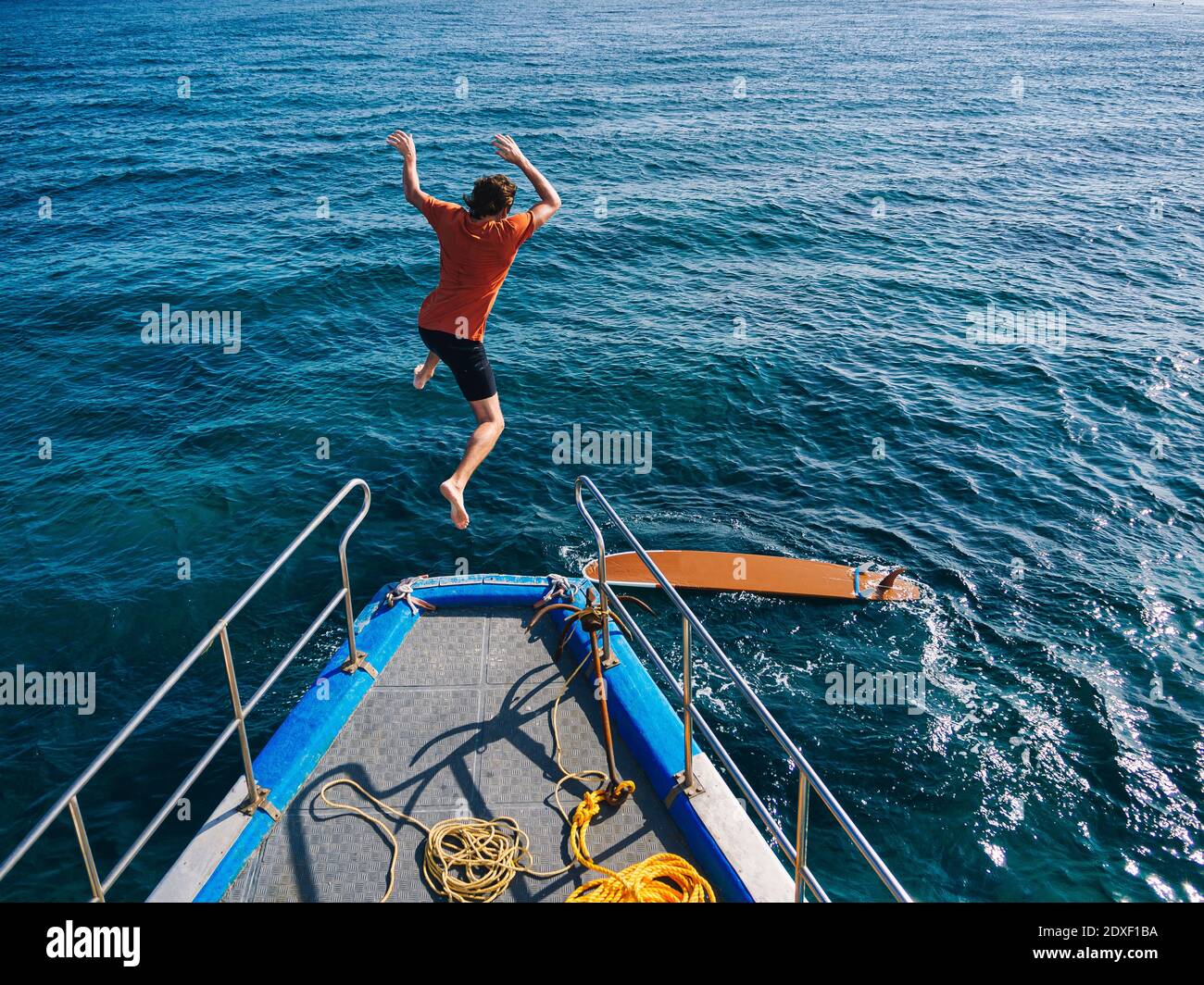 Abenteuerlicher Mann, der vom Bootsdeck zum Surfen abspringt Sonniger Tag Stockfoto