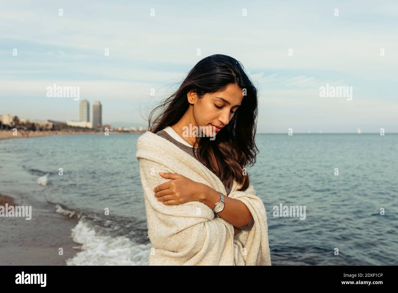 Junge Frau, die am Strand steht und nach unten schaut Stockfoto