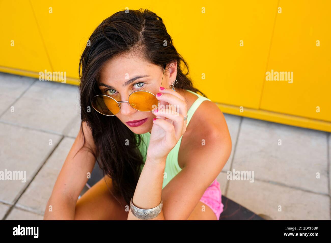Portrait von schönen Mädchen trägt Sonnenbrille auf Longboard sitzen Stockfoto