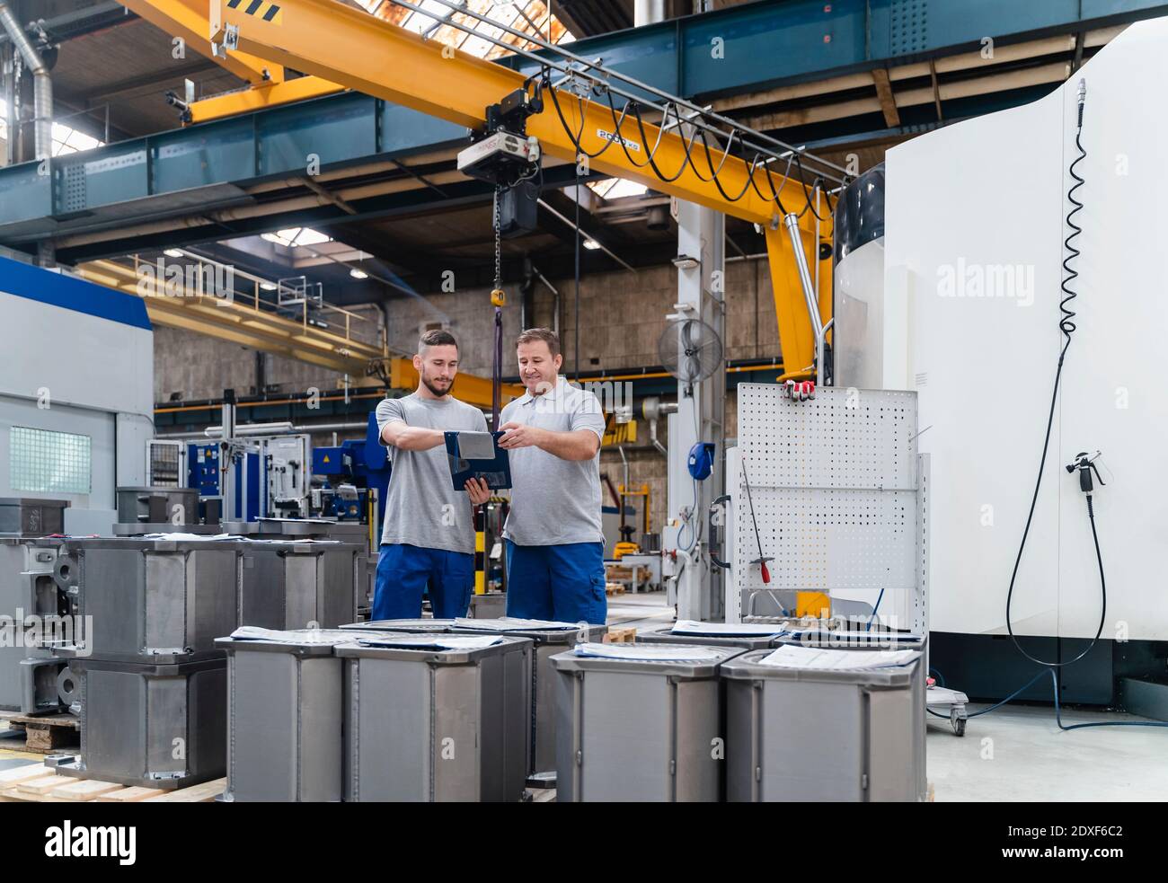 Männliche Mitarbeiter Brainstorming, während bei Maschinen in der Fabrik stehen Stockfoto