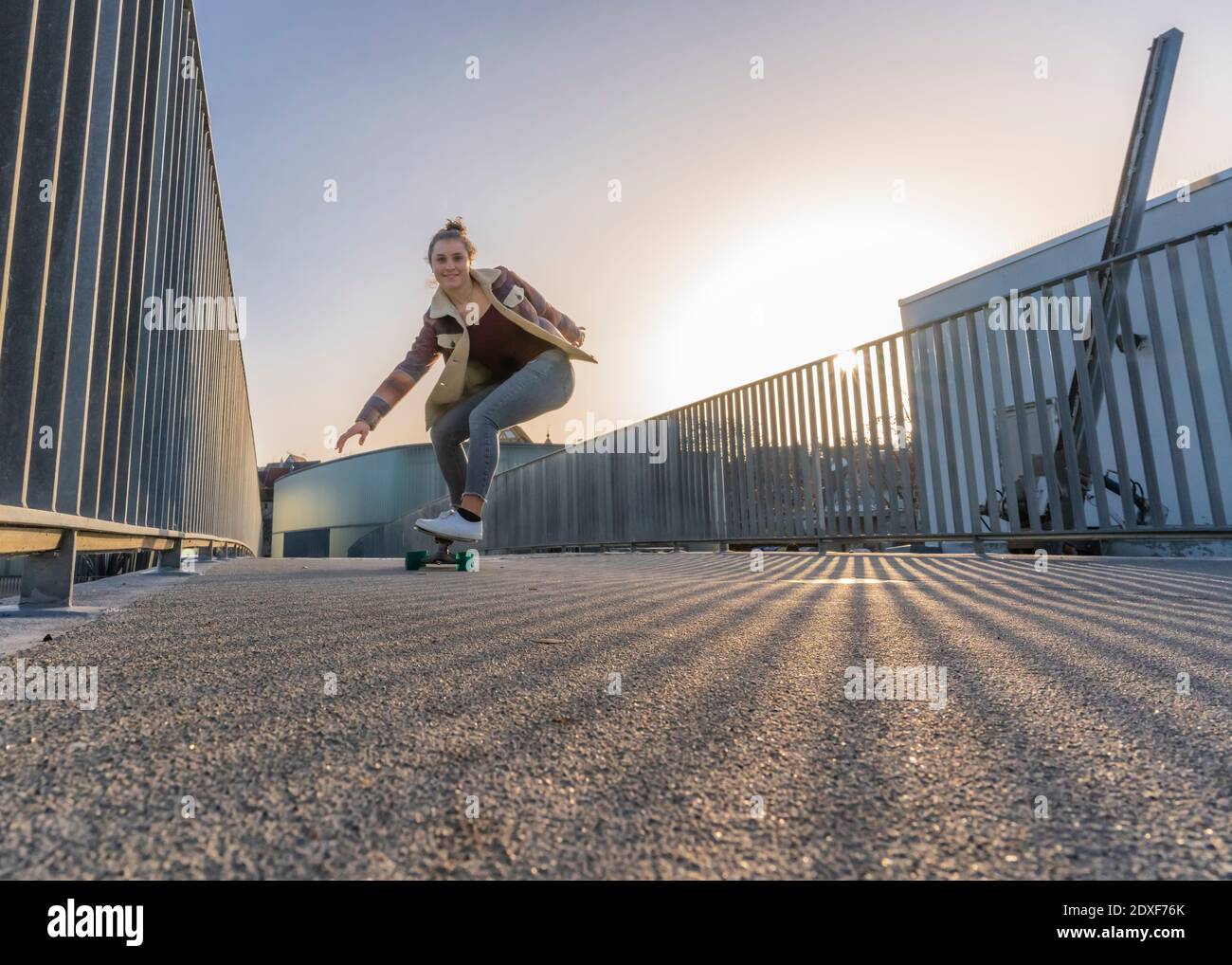 Fröhliches weibliches Skateboarding gegen klaren Himmel bei Sonnenuntergang Stockfoto