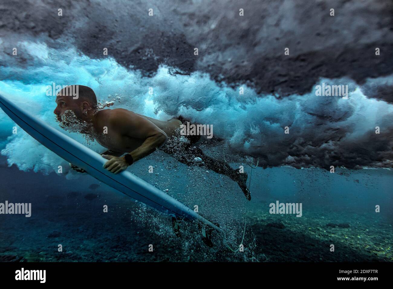 Männliche Surfer Ente Tauchen im Wasser mit Surfbrett auf den Malediven Stockfoto