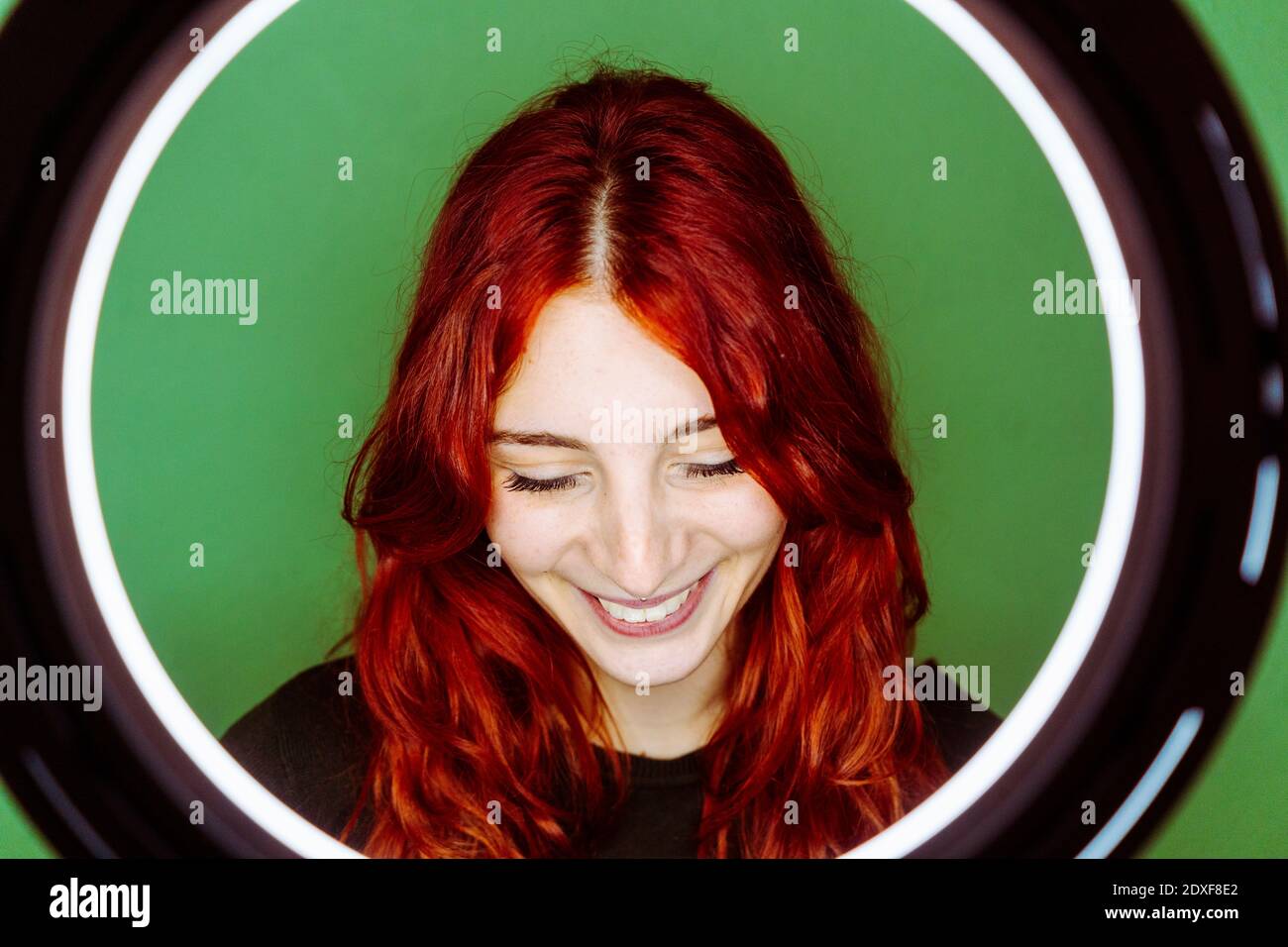 Lächelnd Rothaarige Frau mit Ring-Blitzlicht steht gegen grün Hintergrund Stockfoto