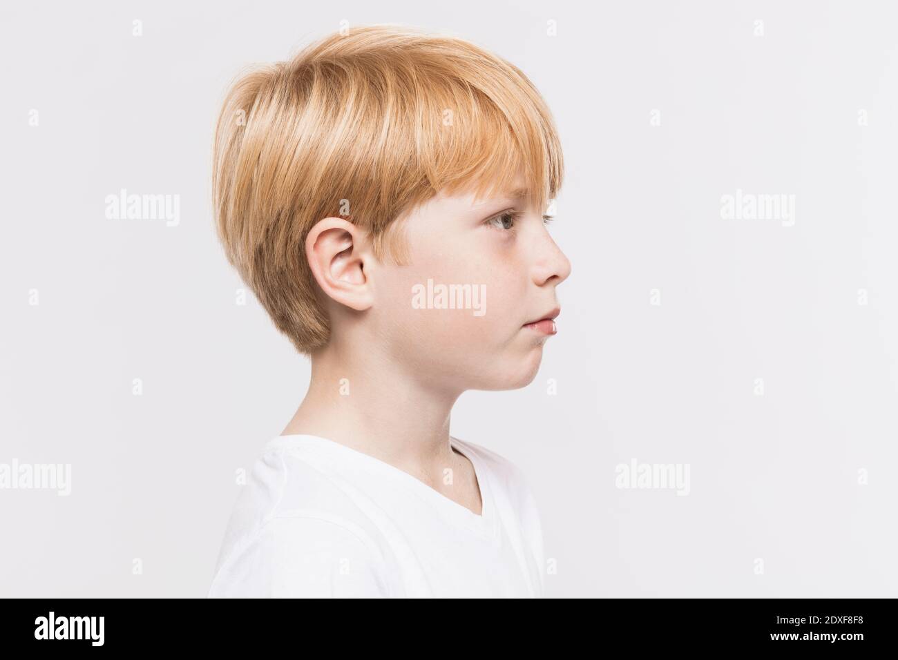 Nachdenklicher Junge mit blonden Haaren vor weißem Hintergrund Stockfoto