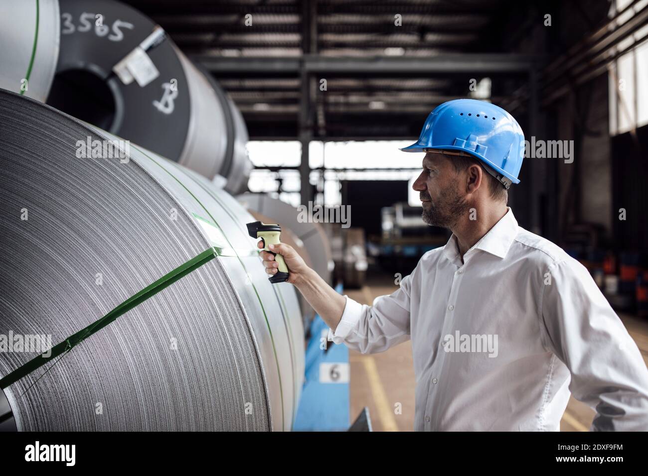 Man scannt Barcode auf Stahlrollen, während man in der Industrie steht Stockfoto