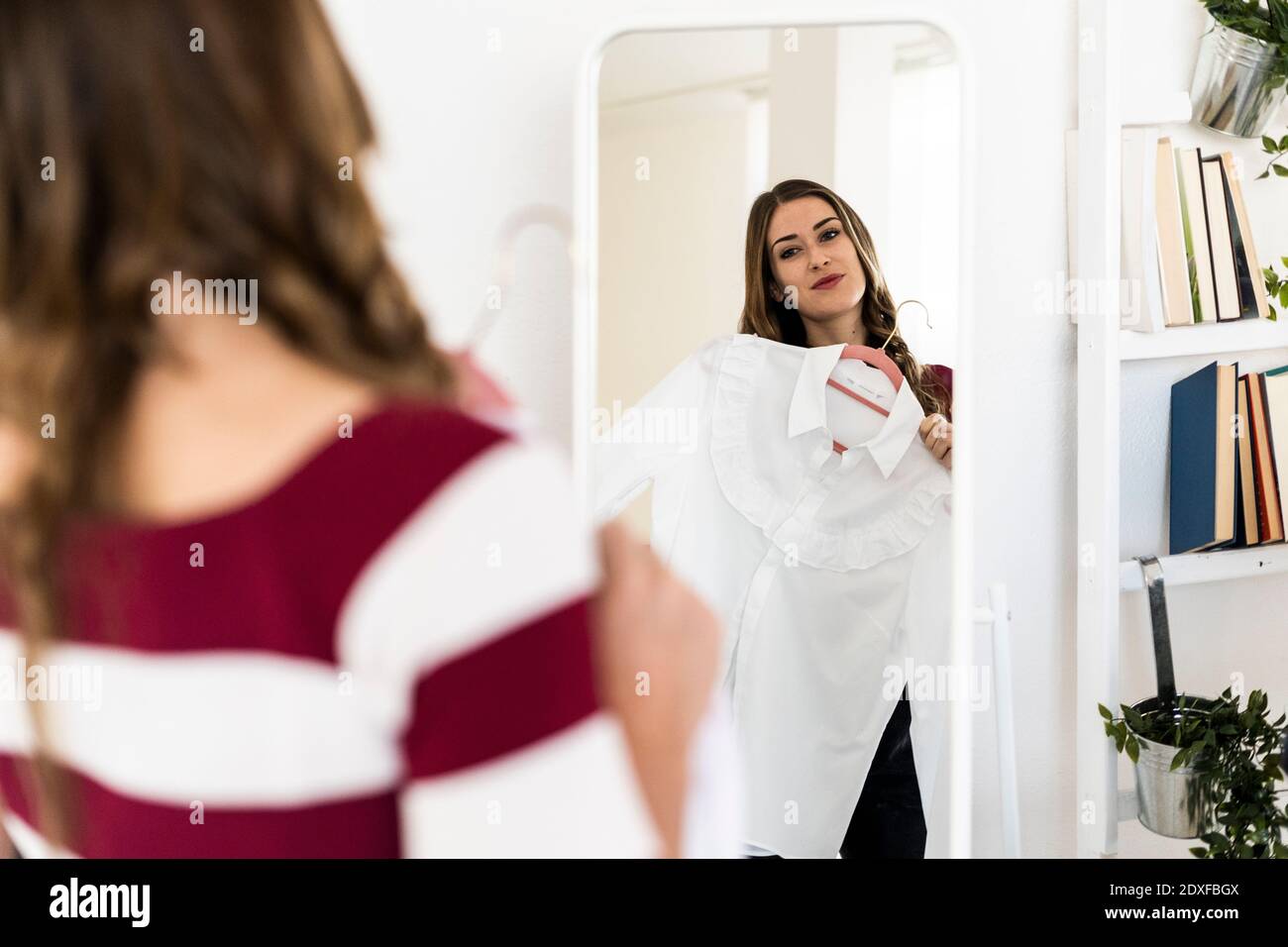 Weibliche Modedesignerin, die oben hält, während sie Spiegel in betrachtet studio Stockfoto