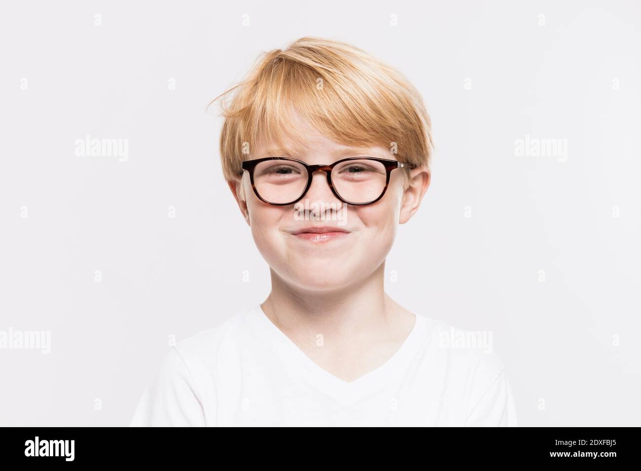Lächelnder Junge in Brillen vor weißem Hintergrund Stockfoto