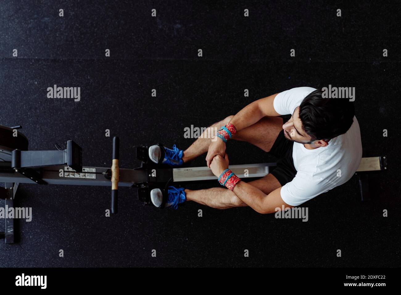 Sportler, der eine Pause beim Sitzen auf dem Rudergerät bei nimmt Fitnessraum Stockfoto