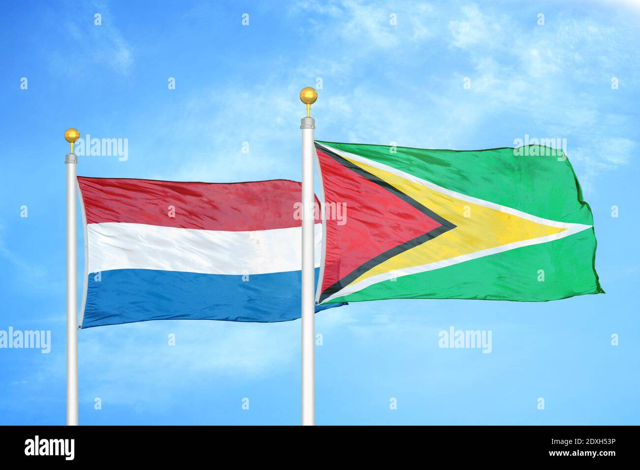 Niederlande und Guyana zwei Flaggen auf Fahnenmasten und blauer Himmel Stockfoto