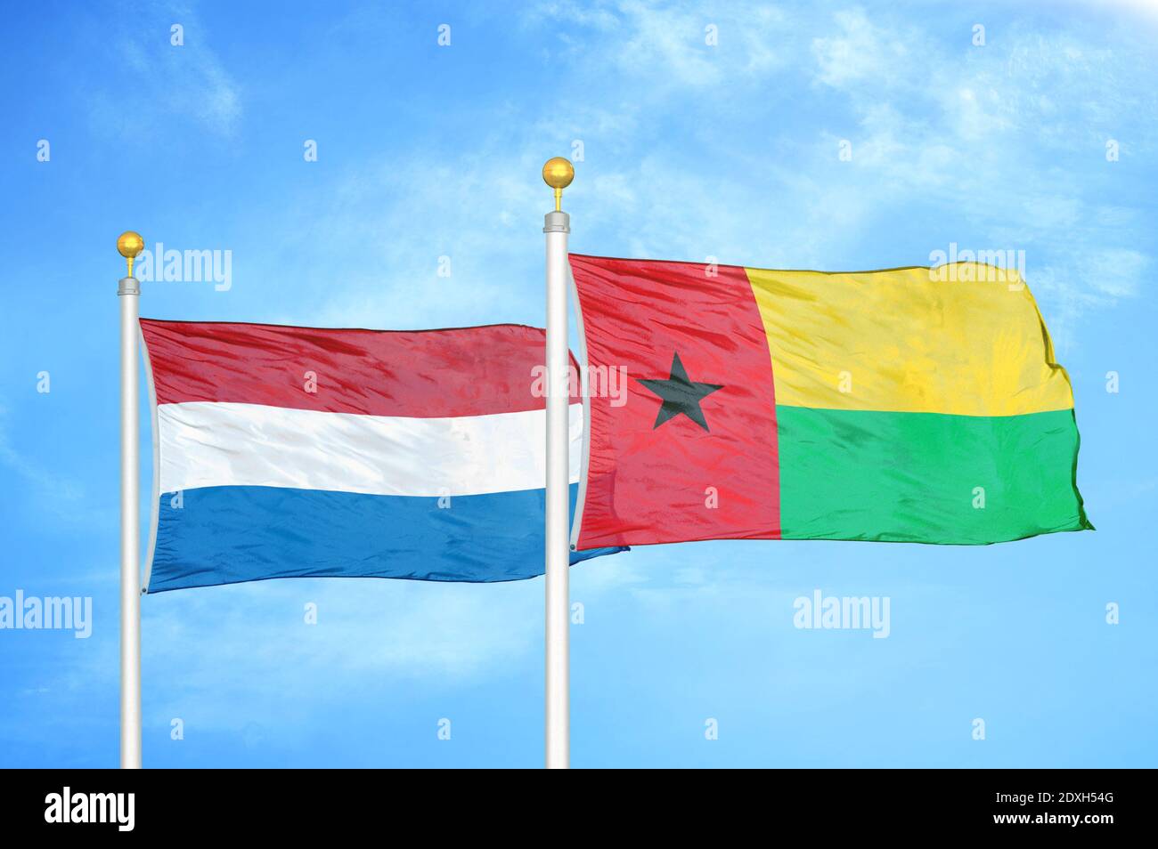 Niederlande und Guinea-Bissau zwei Flaggen auf Fahnenmasten und blauer Himmel Stockfoto