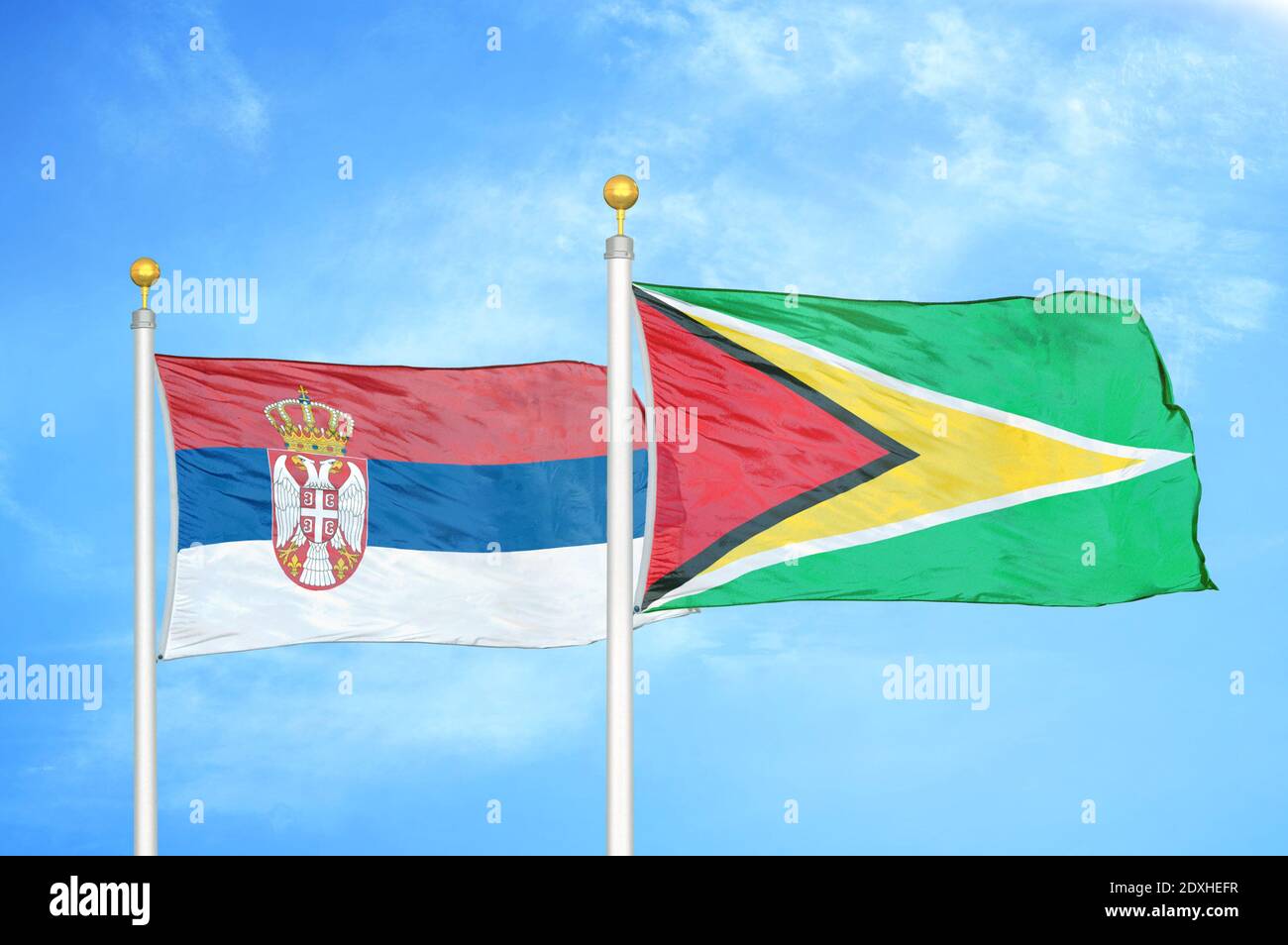 Serbien und Guyana zwei Flaggen auf Fahnenmasten und blauer Himmel Stockfoto