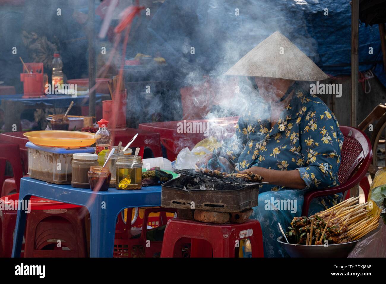 Street Food Verkäufer sitzt vor einem rauchenden Grill Stockfoto