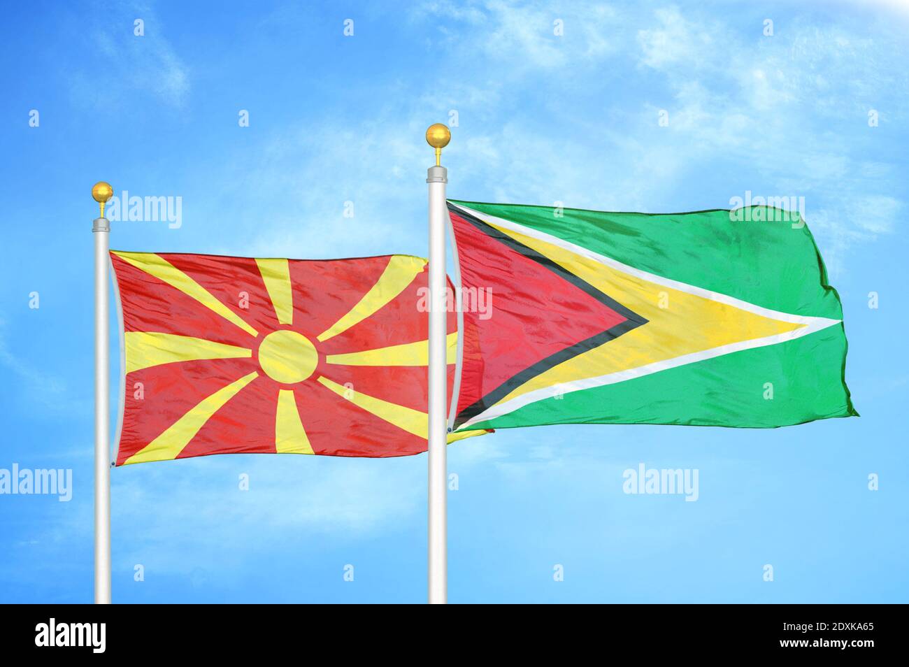 Nord-Mazedonien und Guyana zwei Flaggen auf Fahnenmasten und blau Himmel Stockfoto