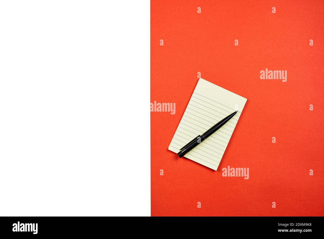 Ein Notizblock mit Stift auf dem weißen und roten geteilten Hintergrund. Blick von oben Stockfoto
