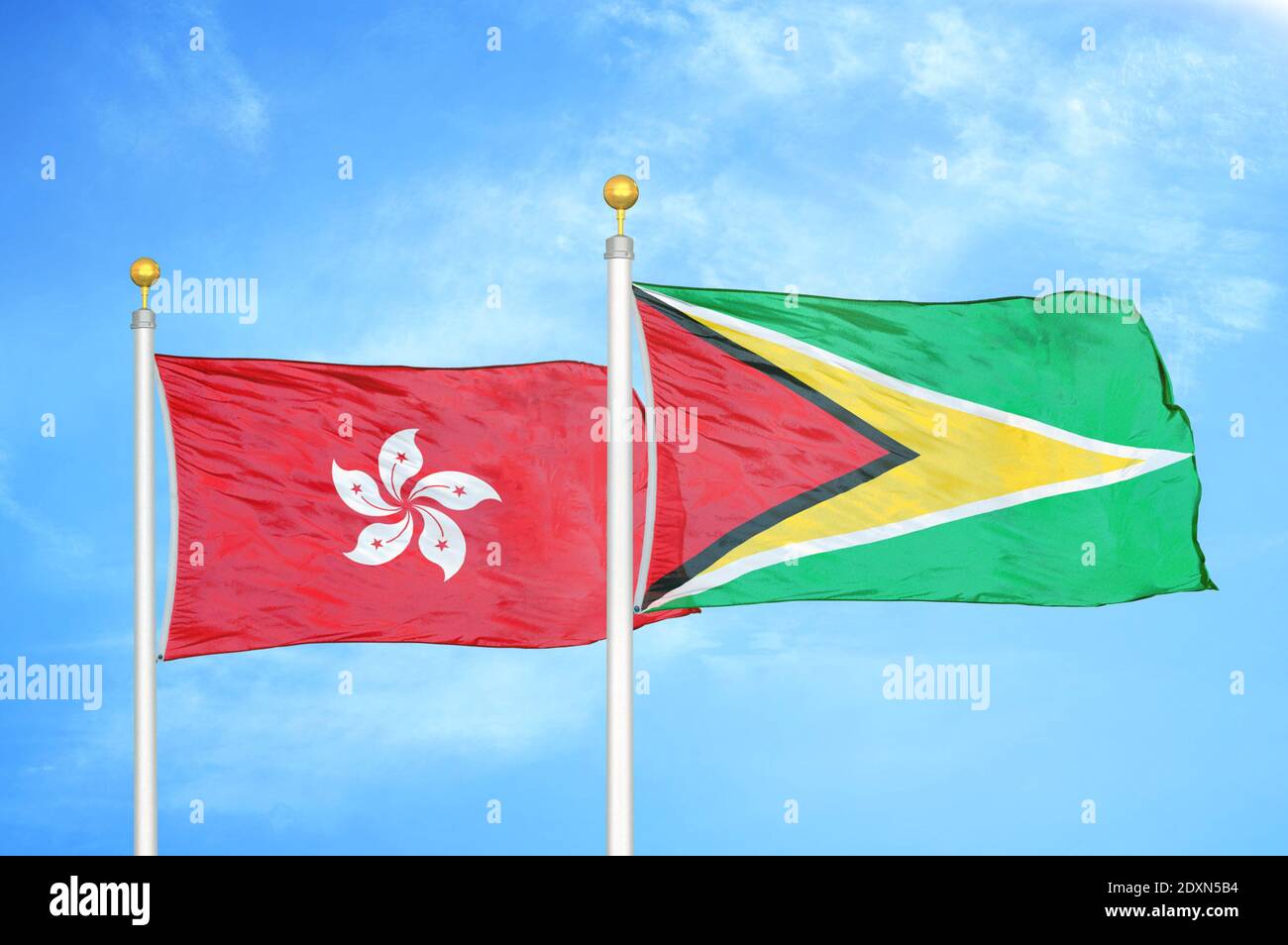 Hongkong und Guyana zwei Flaggen auf Fahnenmasten und blau wolkiger Himmel Stockfoto