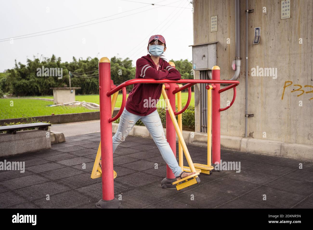 Junge asiatische Frau trägt Gesichtschirurgie Maske spielen im Kinderpark in Hsinchu, Taiwan Stockfoto