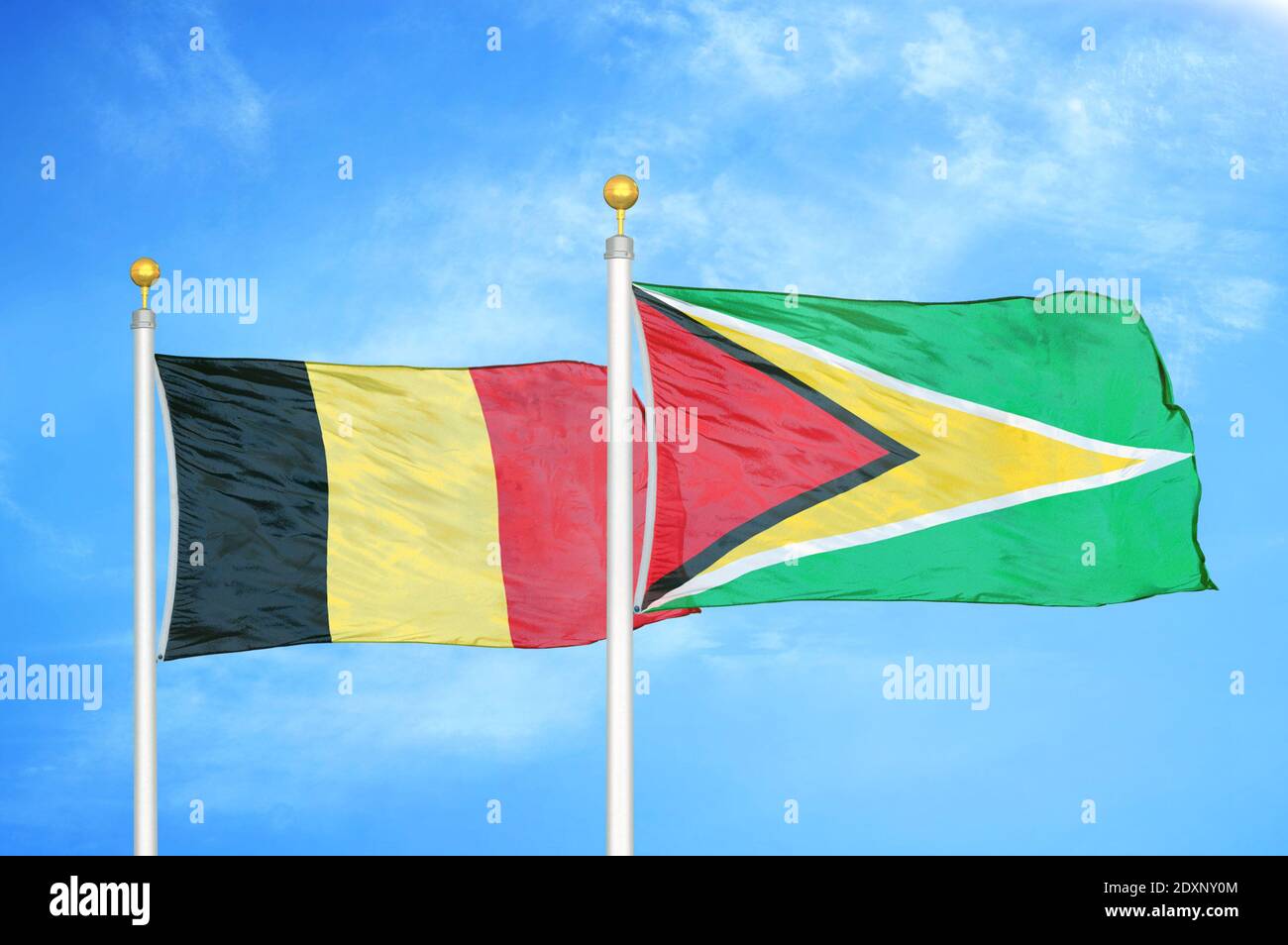 Belgien und Guyana zwei Flaggen auf Fahnenmasten und blau bewölkt Himmel Stockfoto
