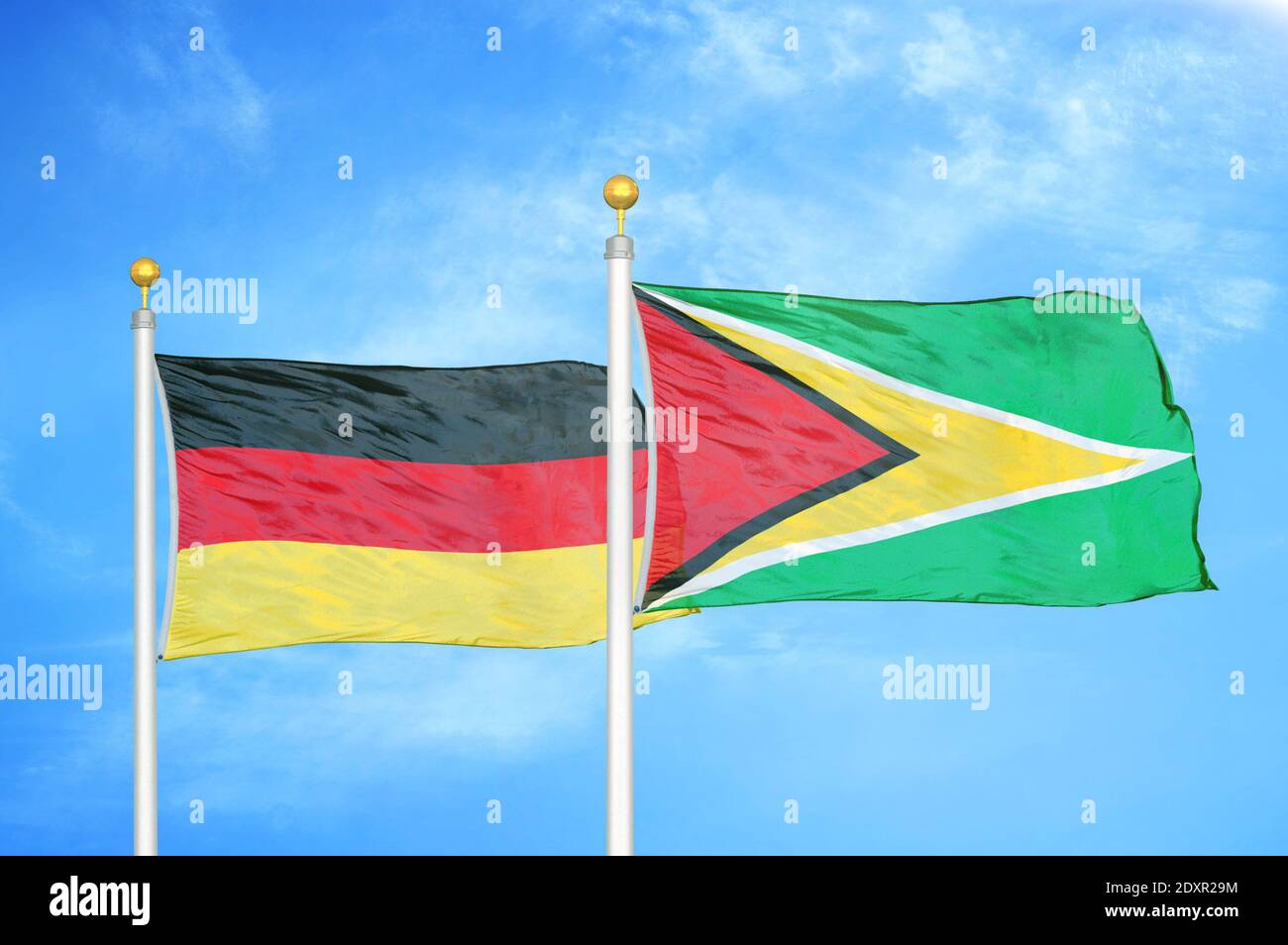 Deutschland und Guyana zwei Flaggen auf Fahnenmasten und blau bewölkt Himmel Stockfoto