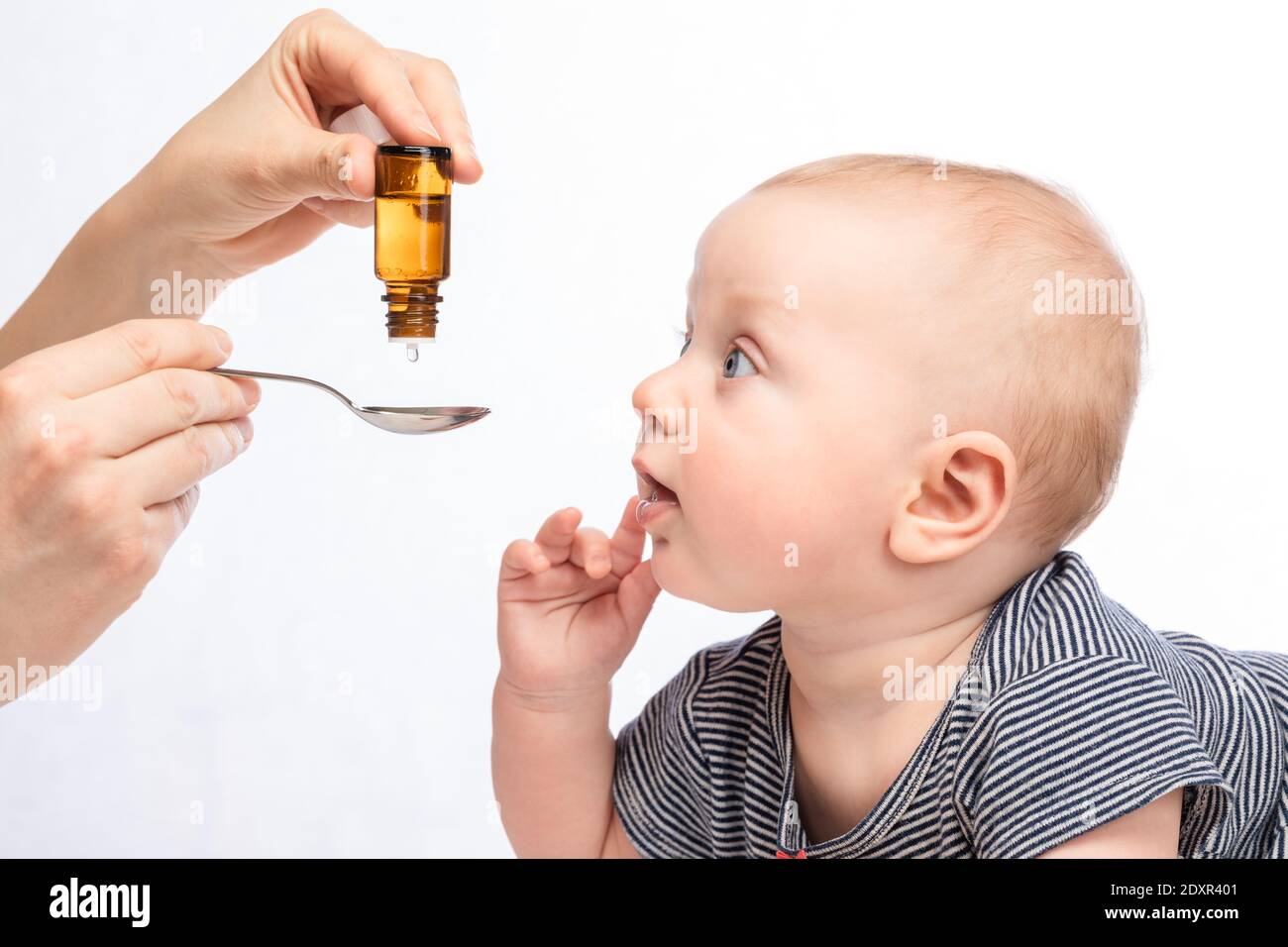 Mutter Fütterung Baby Junge mit Vitamin oder flüssige Medizin mit Löffel Stockfoto