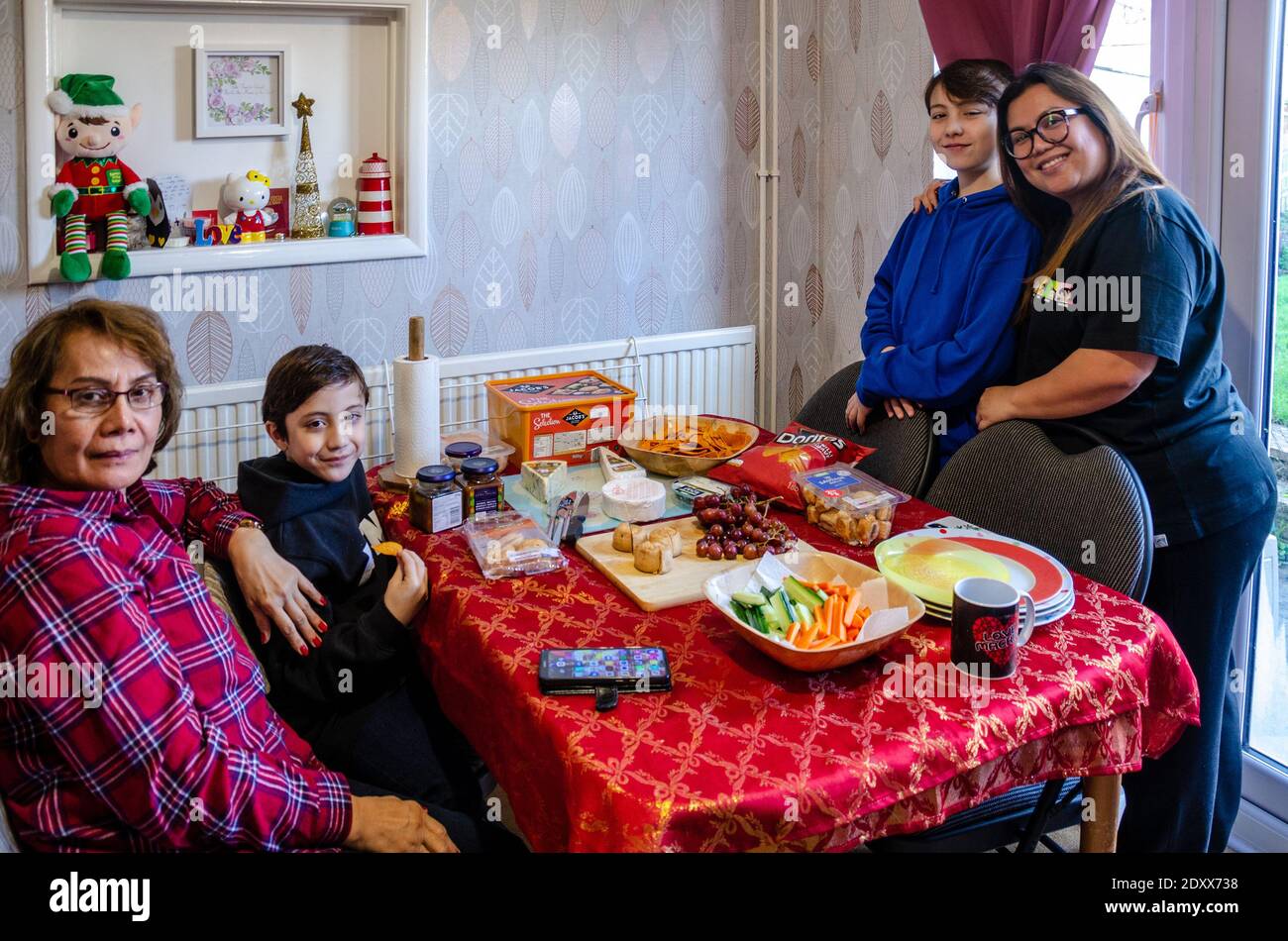 Eine glückliche Familie aus drei Generationen posiert zu Weihnachten gemeinsam für ein Porträt um einen Tisch mit Fingerfood. Stockfoto