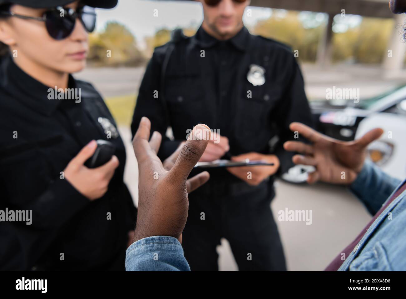 afroamerikanischer Mann Opfer Gestik in der Nähe Polizisten auf verschwommen Hintergrund im Freien Stockfoto