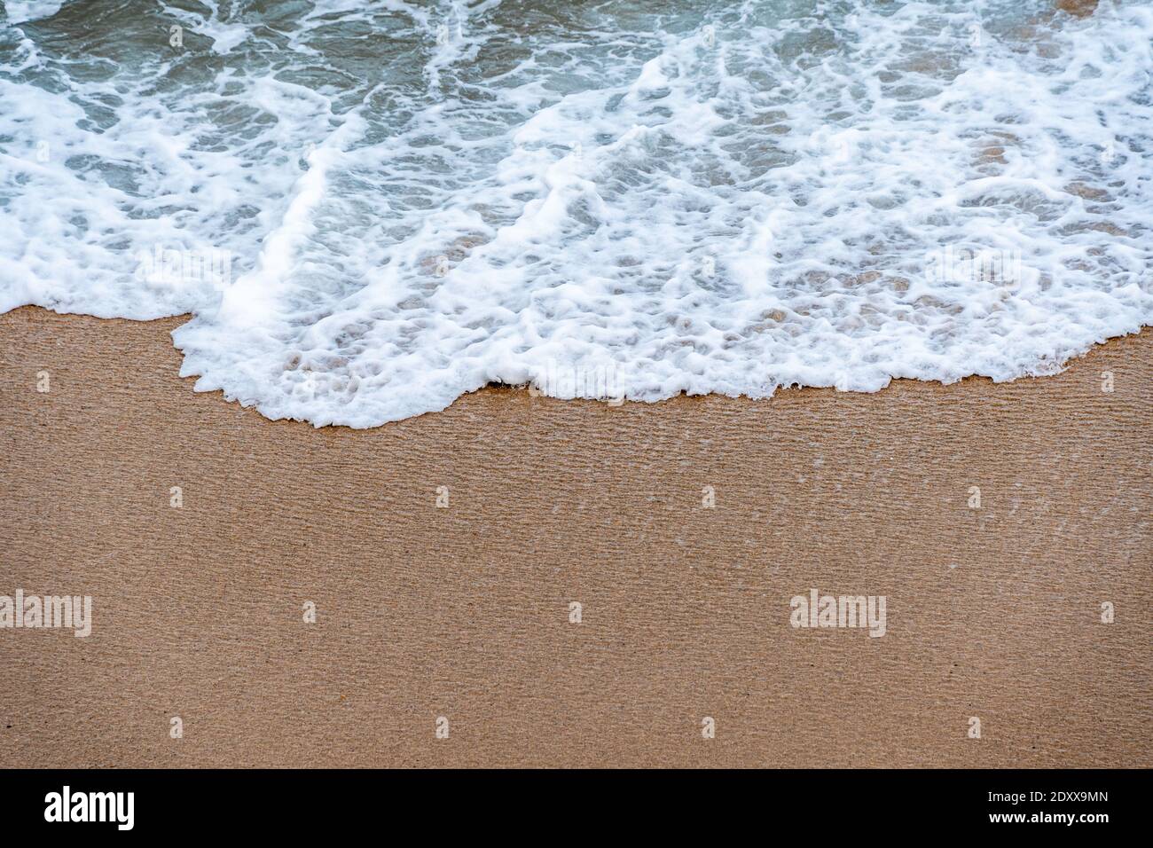 Meereswelle kommt auf den Sand. Nahaufnahme von oben. Textur für den Hintergrund. Platz für Text kopieren Stockfoto