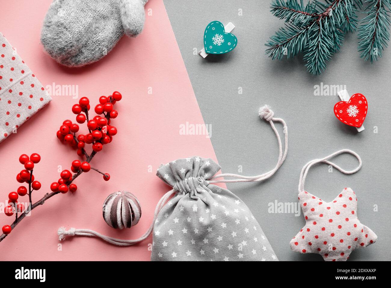 Nachhaltige Naturgeschenke für Zero Waste Weihnachten.Handschuhe, weiches Spielzeug, Holzpflöcke und natürliche Beeren. Lagenlook rosa grau Papier Hintergrund. Stockfoto