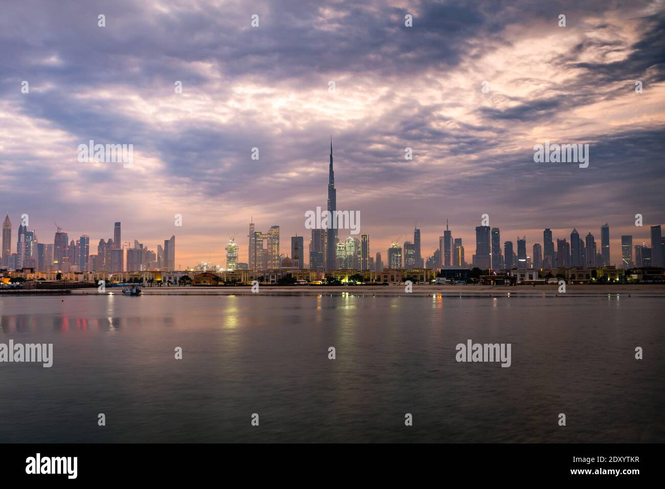 Sonnenaufgang in Dubai mit Blick auf den bewölkten Himmel vom Boot oder Meer. Morgens geht die Sonne über den Wolkenkratzern der VAE auf. Dubai Strand, Küste, Ufer Stockfoto