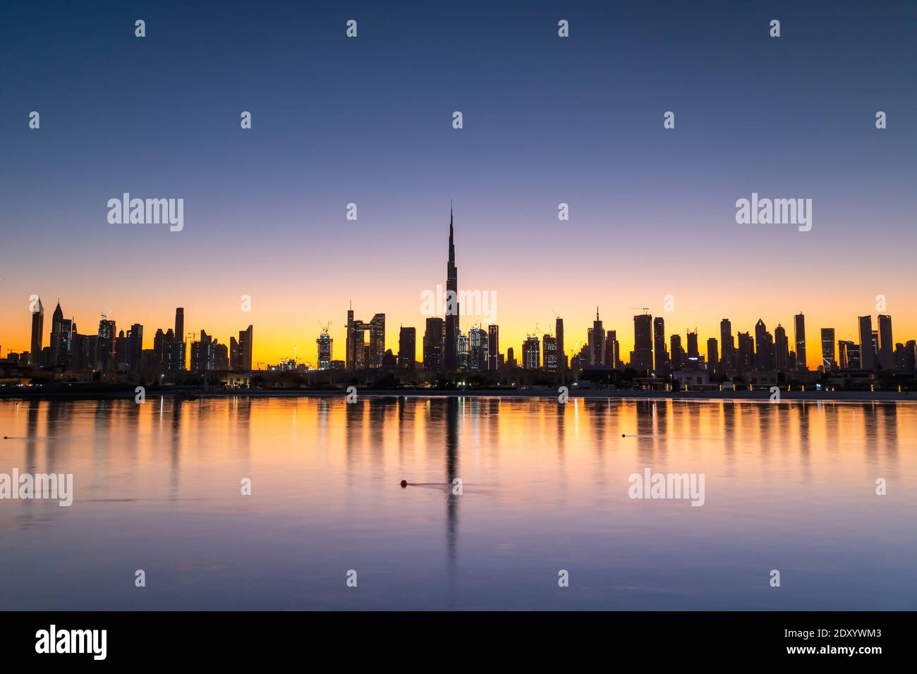 Sonnenaufgang in Dubai mit klarem blauen Himmel Blick vom Boot oder Meer. Morgens geht die Sonne über den Wolkenkratzern der VAE auf. Dubai Strand, Küste, Ufer Stockfoto