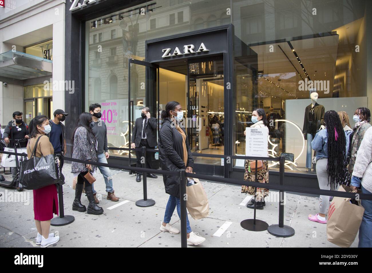 Die Menschen standen, angemessen sozial distanziert, vor einem ZARA-Laden in Manhattan, um am Black Friday 2020 während der Covid-19-Pandemie einzukaufen. Stockfoto