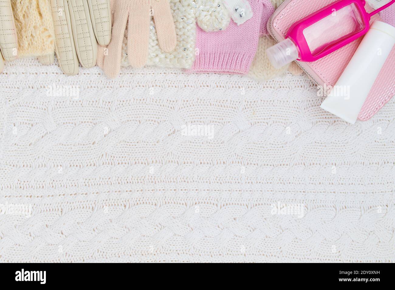 Winter flach legen mit Handcreme, Fäustlinge, Handschuhe und Desinfektionsmittel auf weiß gestrickten Hintergrund. Stockfoto