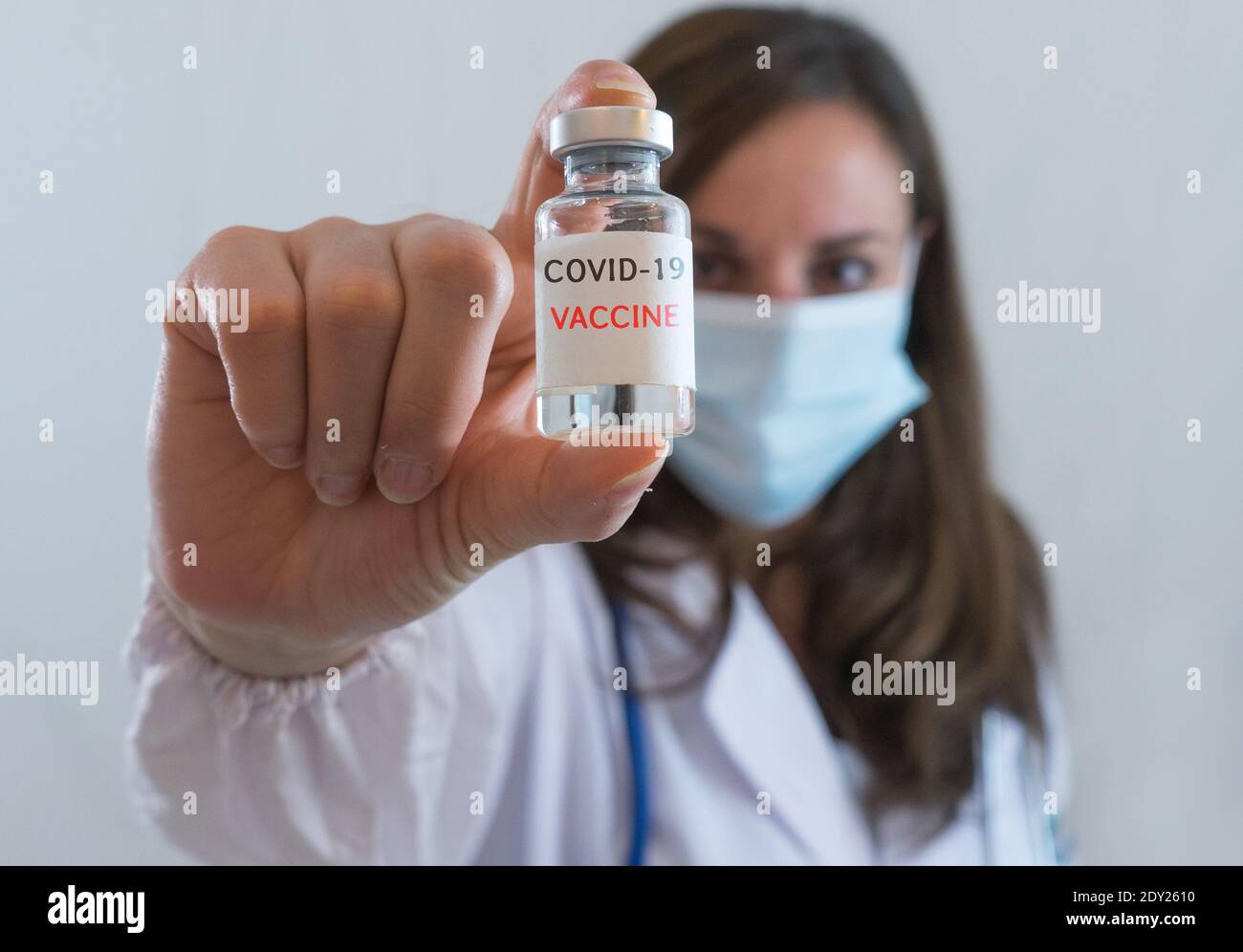 Kaukasische Frau Arzt oder Krankenschwester in Uniform und Handschuhe Tragen Gesichtsmaske schützende im Labor halten Impfstoffflasche und Auf Flasche hat 'COVID-19 VACCI Stockfoto