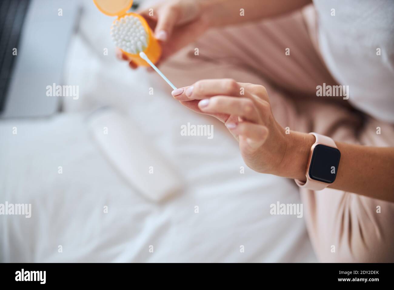 Fokussiertes Bild von q-Tips in den Händen der Frau während des Sitzens Das Zimmer drinnen Stockfoto