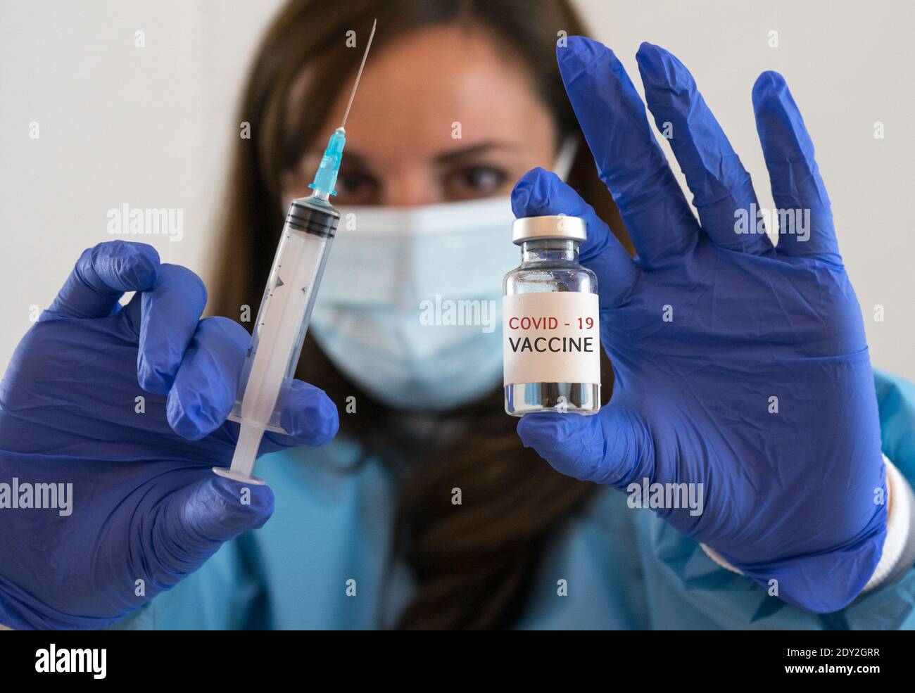Kaukasische Frau Arzt oder Krankenschwester in Uniform und Handschuhe Tragen Gesichtsmaske Schutz in Labor halten Nadel Spritze Medikament Und Medizin Fläschchen Impfstoff bo Stockfoto