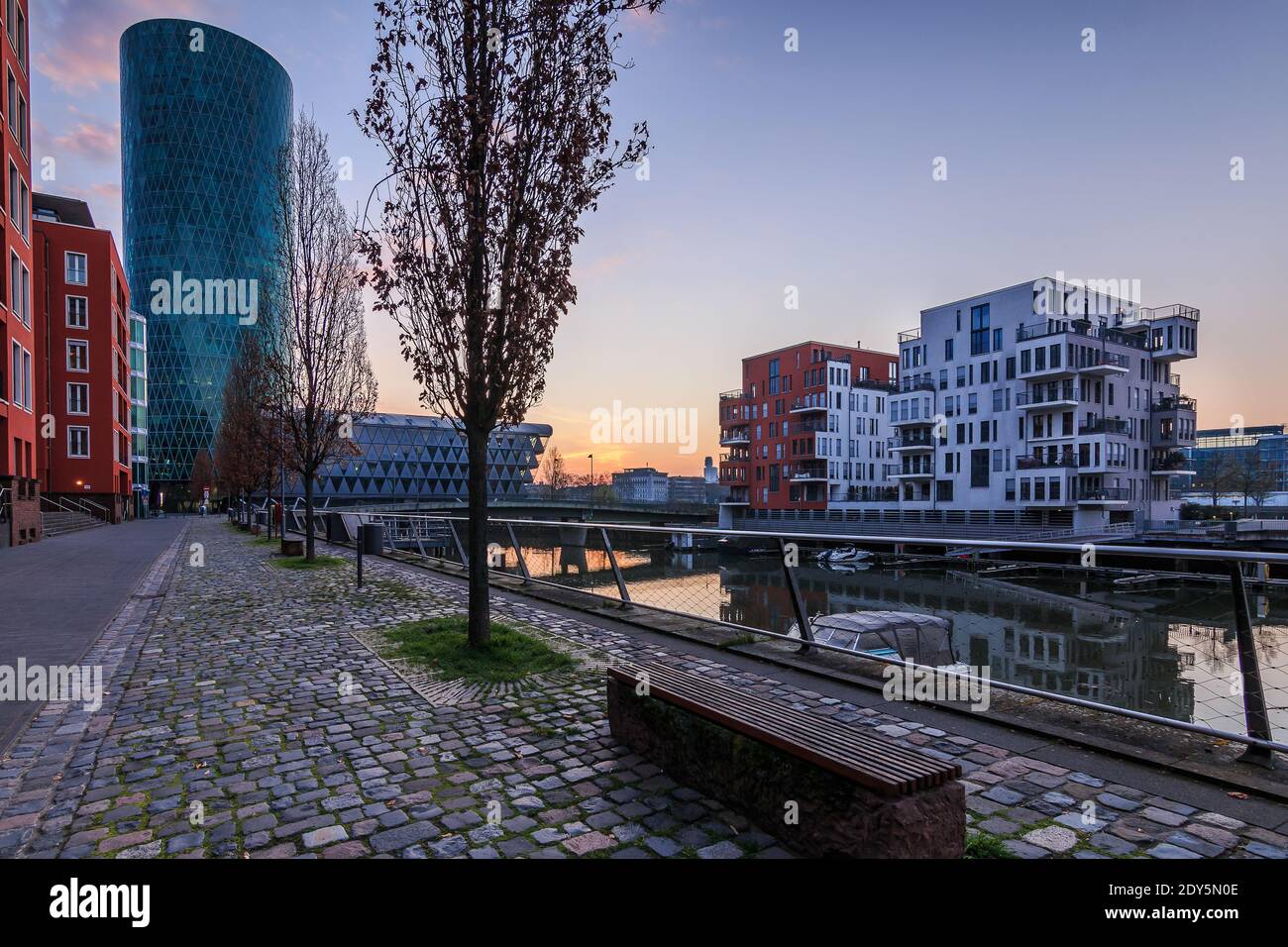 Kanal in Frankfurt am Morgen vor Sonnenaufgang in einem Wohngebiet. Blauer Himmel zwischen den Gebäuden und dem Fluss im westlichen Hafen. Straße Stockfoto