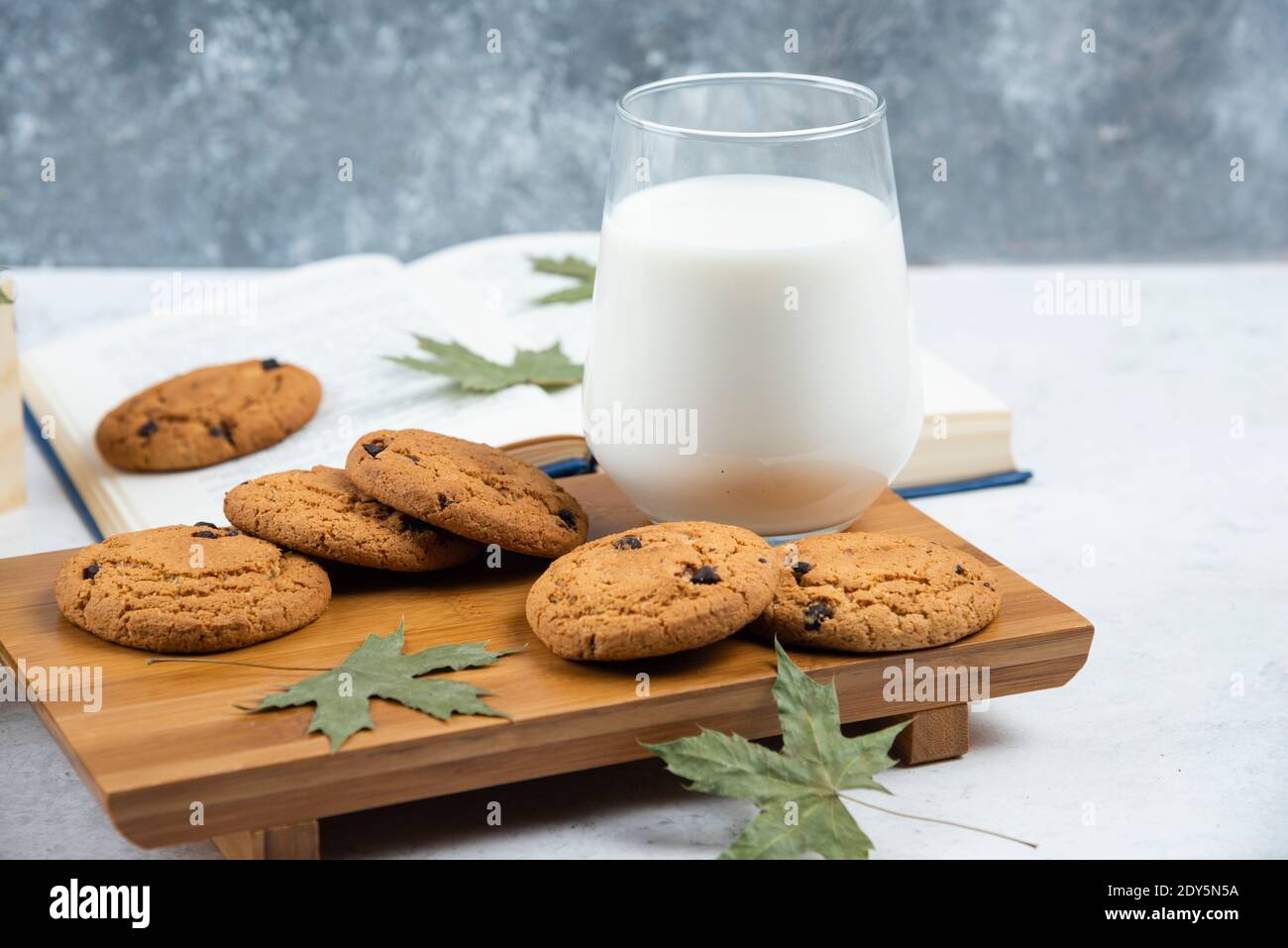 Eine Tasse Milch mit Schokoladenkeksen auf einem Schneidbrett aus Holz Stockfoto