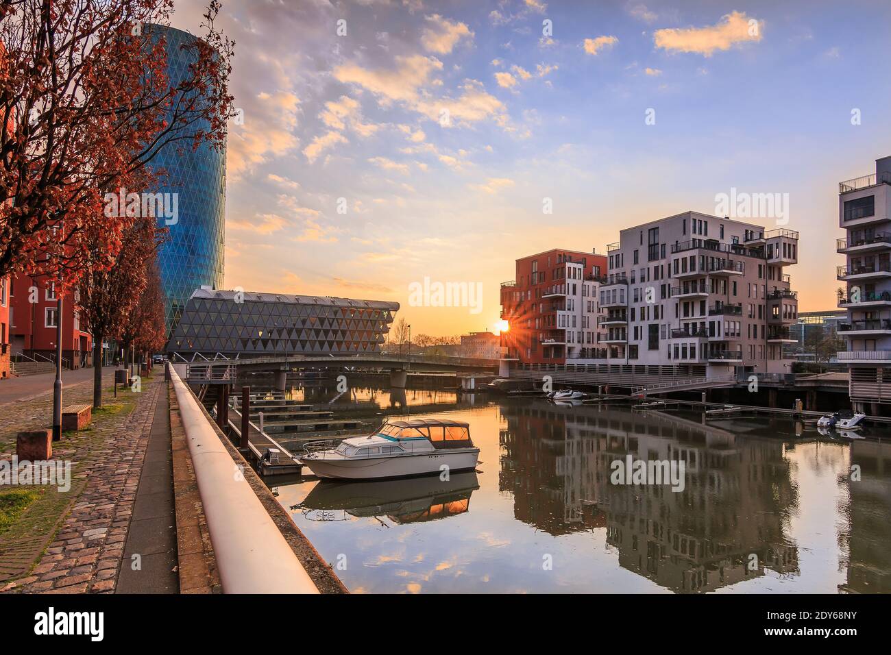 Westhafen mit Kanal vom Main in Frankfurt am Morgen mit Sonnenaufgang und Wolken im Wohngebiet. Blauer Himmel zwischen Gebäuden und Fluss Stockfoto