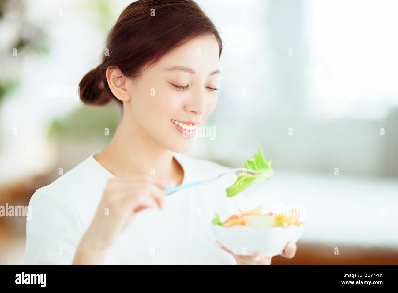 Junge glückliche Frau essen gesunden Salat zu Hause Stockfoto