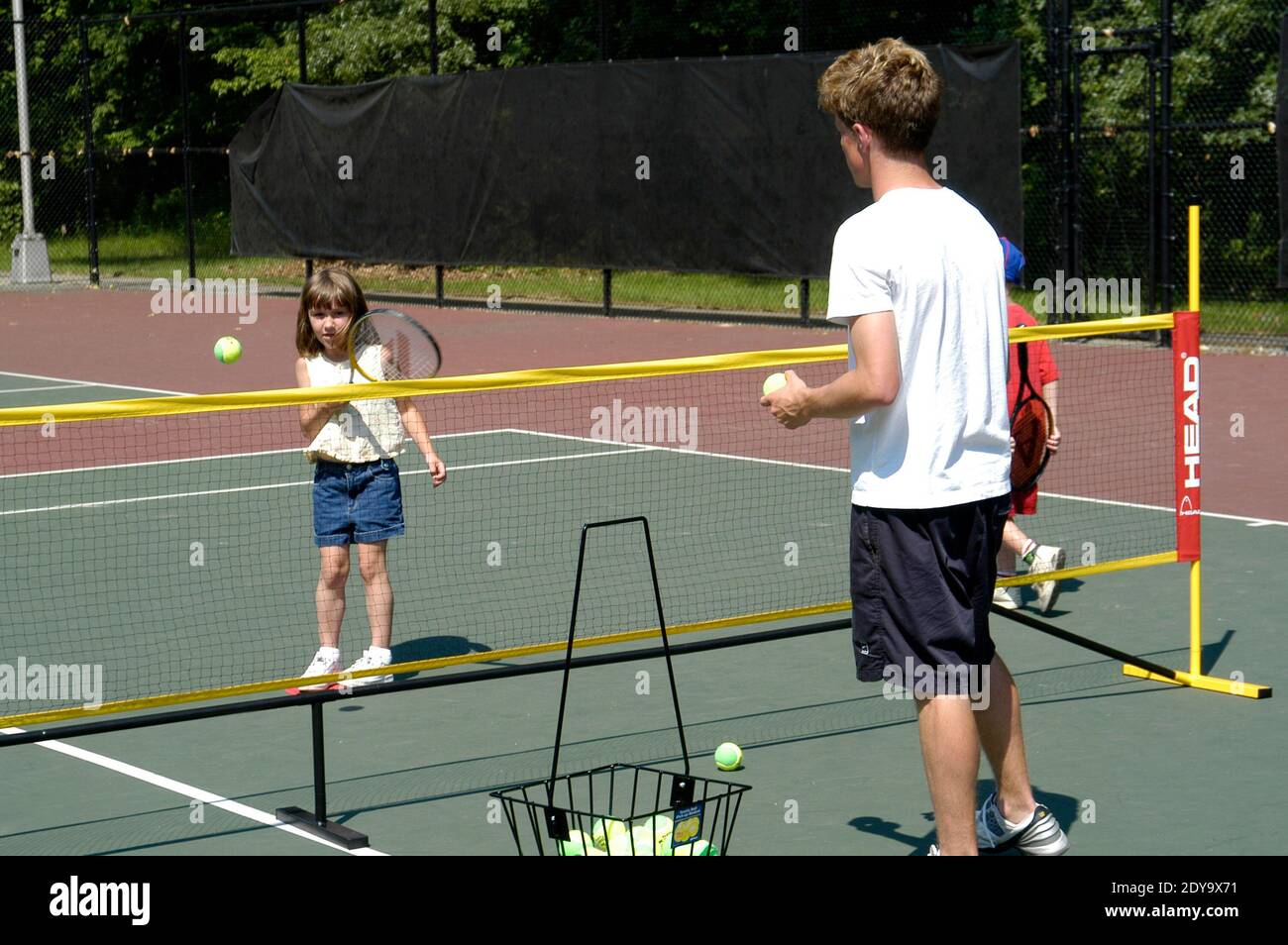 Kleines Mädchen, das Tennisunterricht von einem Einheimischen Gemeinde zu helfen, Kinder lernen das Spiel des Tennis Stockfoto