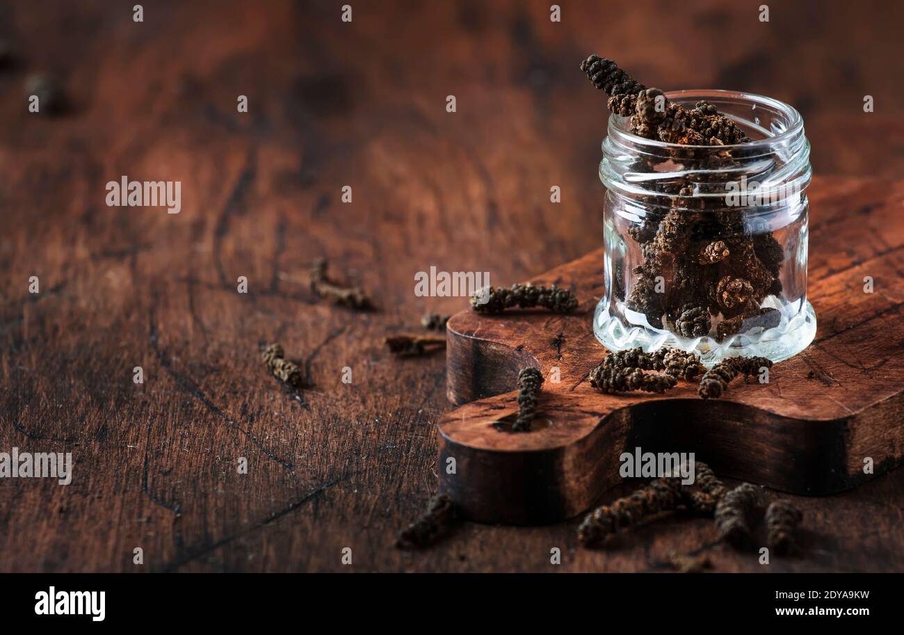 Duftende lange Pfeffer verschüttet aus Glas, vintage Küchentisch Hintergrund, selektive Fokus Stockfoto