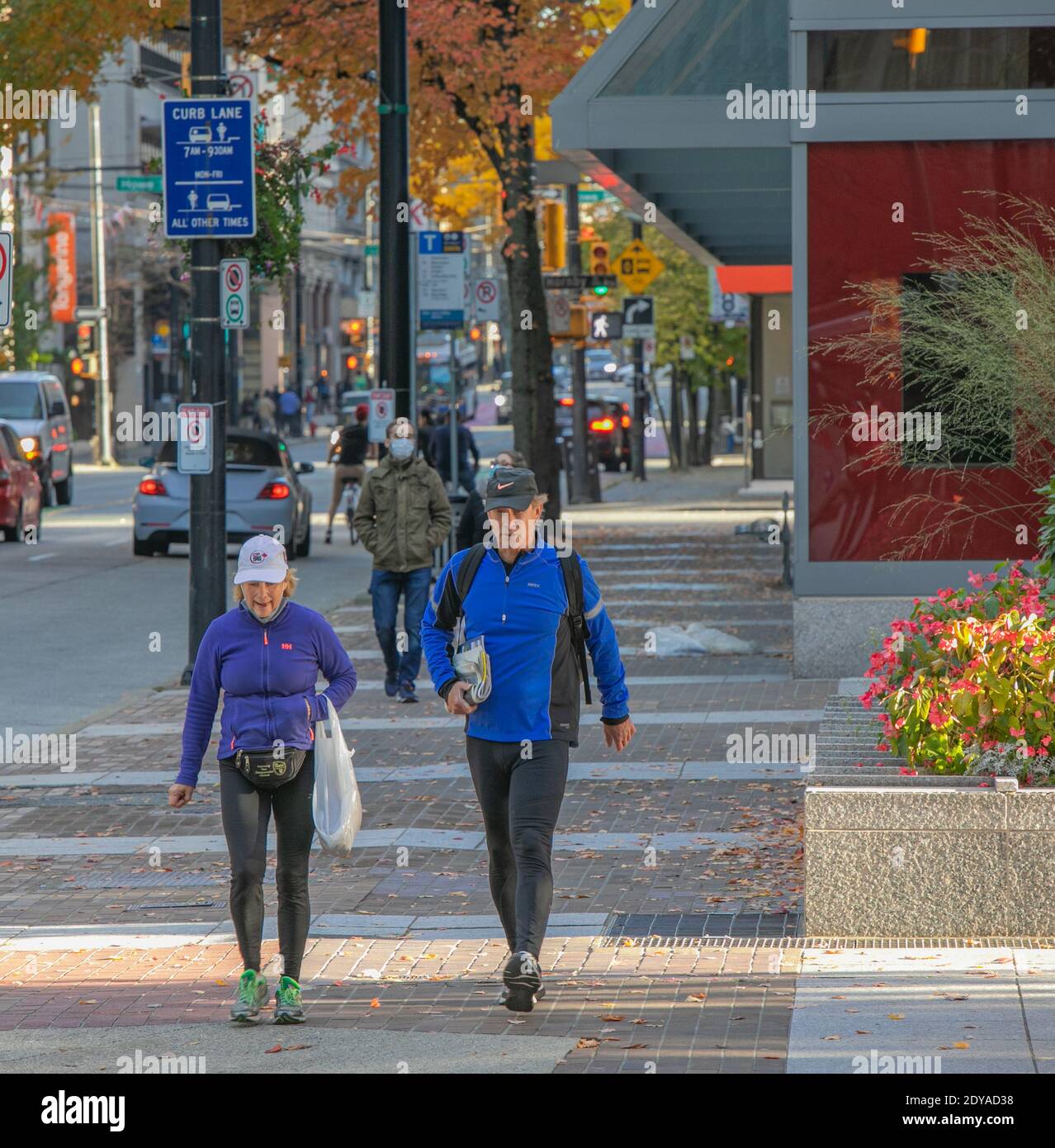 Ein älteres, aktives Paar, das Sportkleidung trägt, geht auf der Straße in Vancouver City, BC, Kanada-November 1,2020. Straßenansicht, Reisefoto, Stockfoto