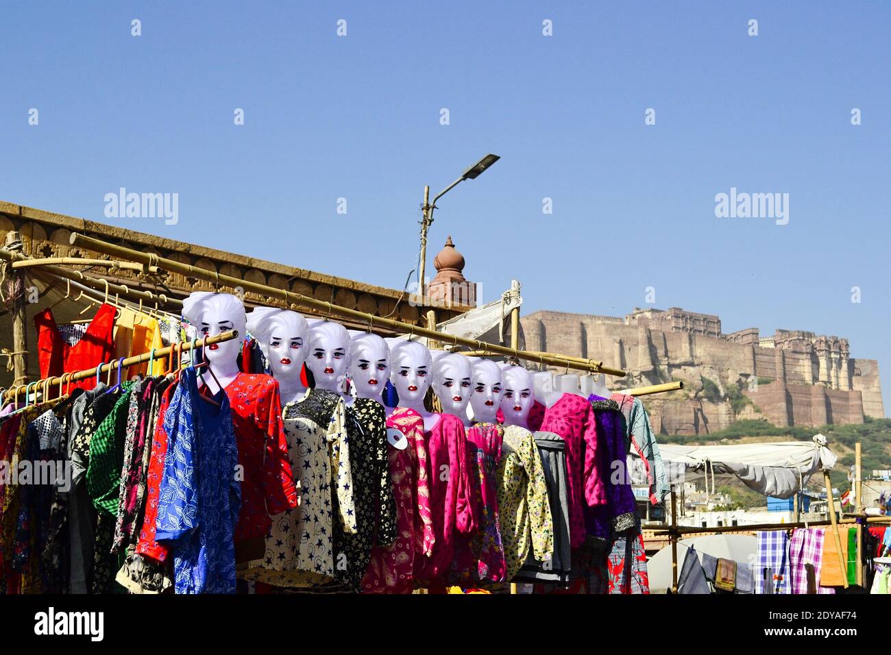 Blick von der Altstadt auf das Mehrangarh Fort. Frau Schaufensterpuppen mit indischem Tuch auf dem Straßenmarkt im Vordergrund. Jodhpur, Rajasthan, Indien. Stockfoto