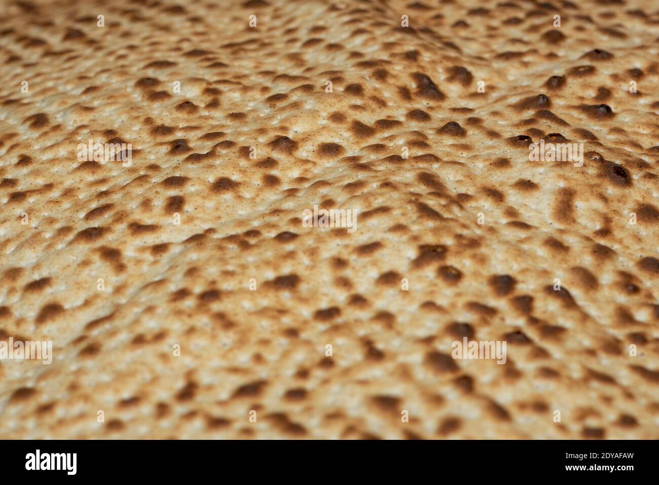 Matzo-Textur, eine Draufsicht auf ein Stück traditionelles Weizen trockenes Brot serviert auf hebräischen Passah. Gebackene Matzo, Matzo-Textur, Hintergrund. Stockfoto