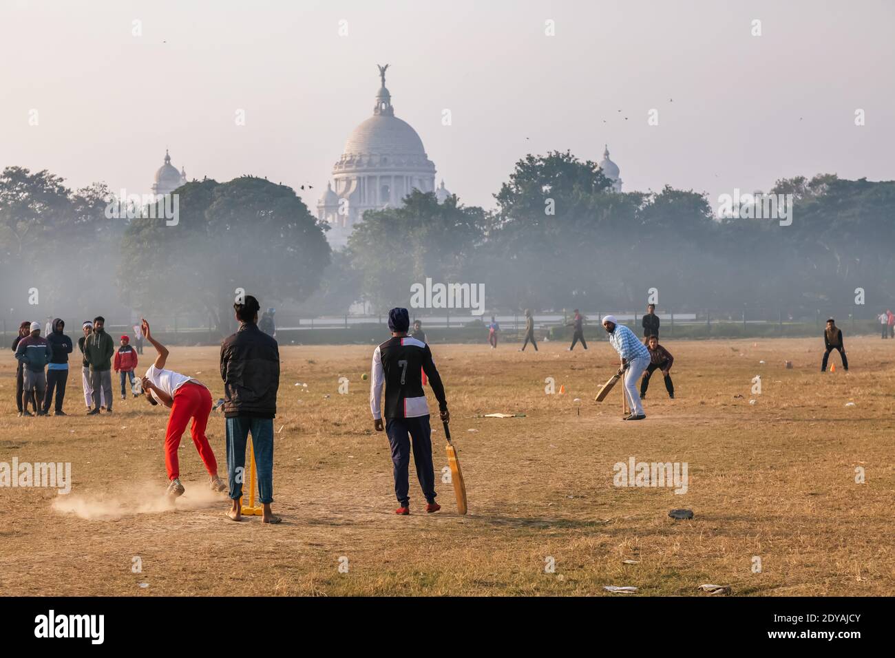 Boys spielen Cricket in Kolkata Maidan Bereich auf einem nebligen Wintermorgen mit Blick auf das Victoria Memorial Monument in der Hintergrund Stockfoto