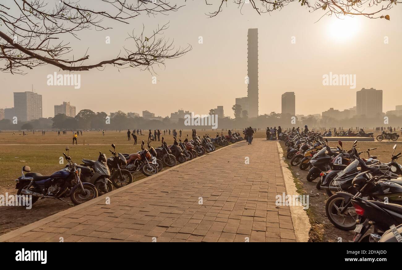 Gefliester Weg mit geparkten Zweirädern im Kalkutta Maidan Bereich Mit Blick auf die Stadtlandschaft an einem nebligen Wintermorgen Stockfoto
