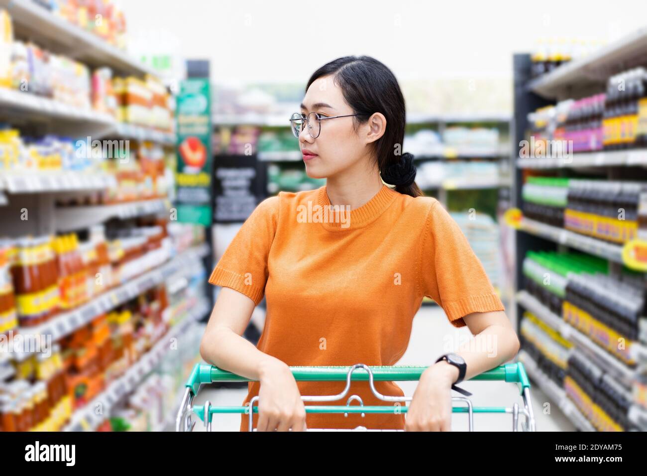 Asiatische Frau genießen Einkaufen in Einkaufszentrum Griff Warenkorb Blick auf Supermarkt Regal Stockfoto
